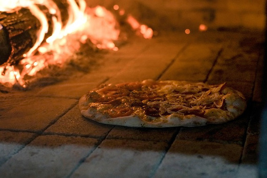 Neapolitanische Pizza im Holzofen bei offener Flamme gebacken